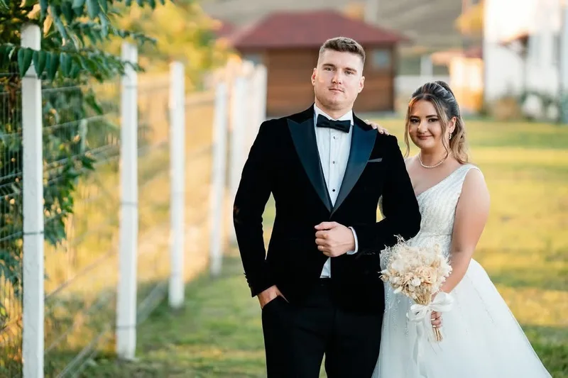 Mire în smoking din catifea neagră, alături de mireasă, în aer liber